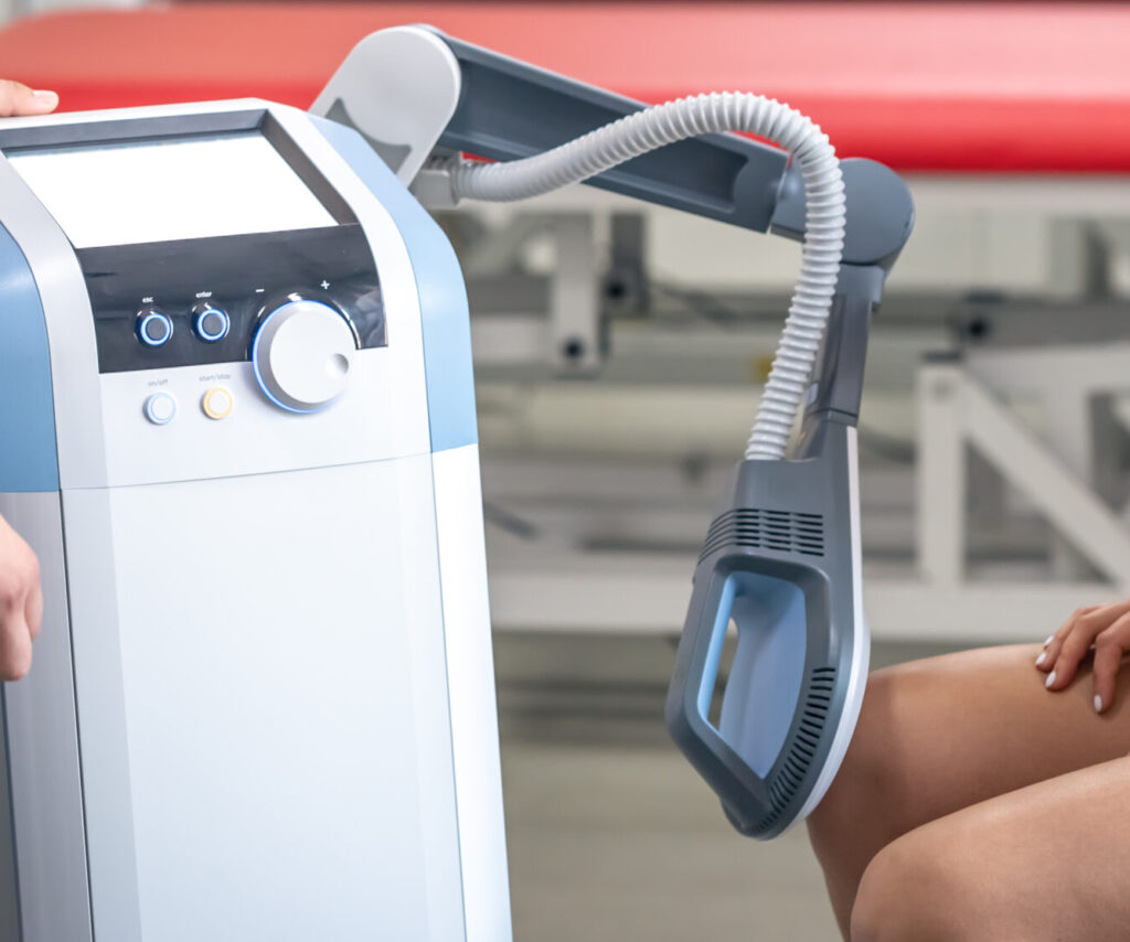 Doctor using machine to treat the knee joints of a patient.